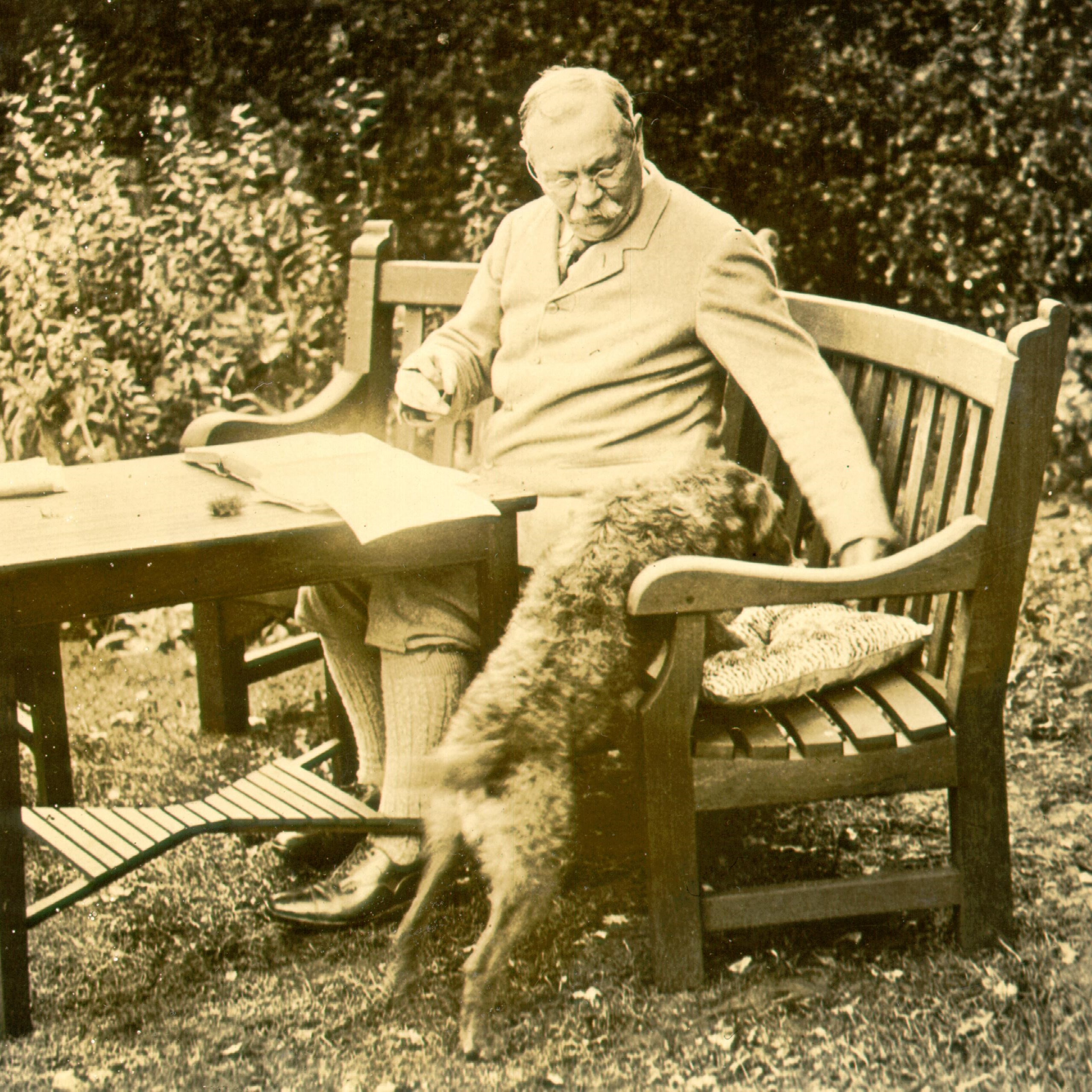 Conan Doyle sitting on a bench with his dog
